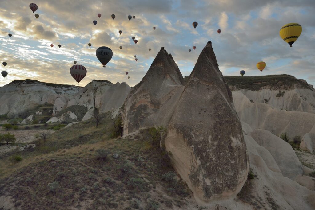 Dozens of hot air balloons rising over the fairy chimneys of Cappadocia at sunrise, Turkey