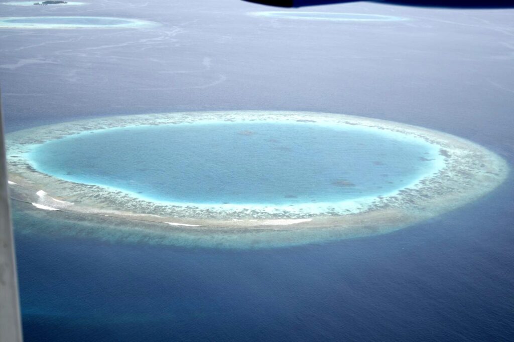 Aerial view of a Maldives coral atoll and lagoon from a seaplane window