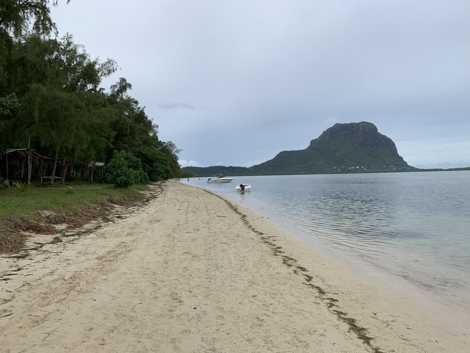 View across a calm Mauritius lagoon to Le Morne Brabant mountain from a quiet sandy beach