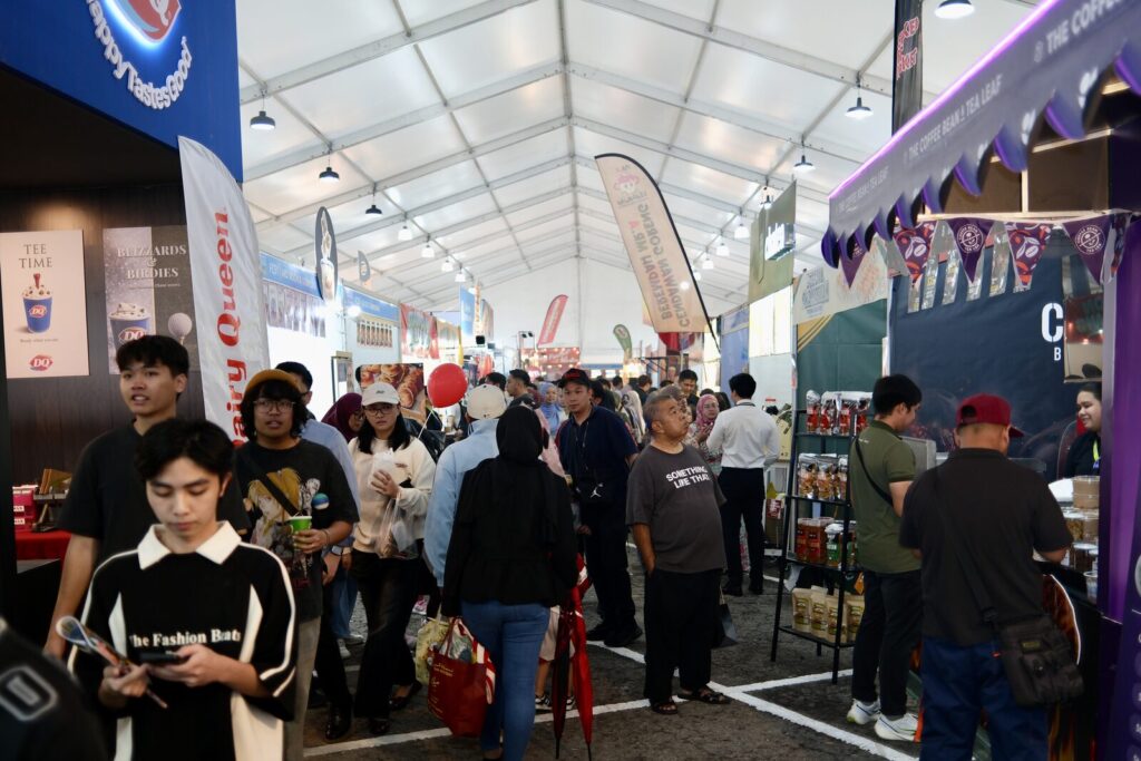 Visitors walking between exhibitor booths at a trade fair — the 'E' in MICE