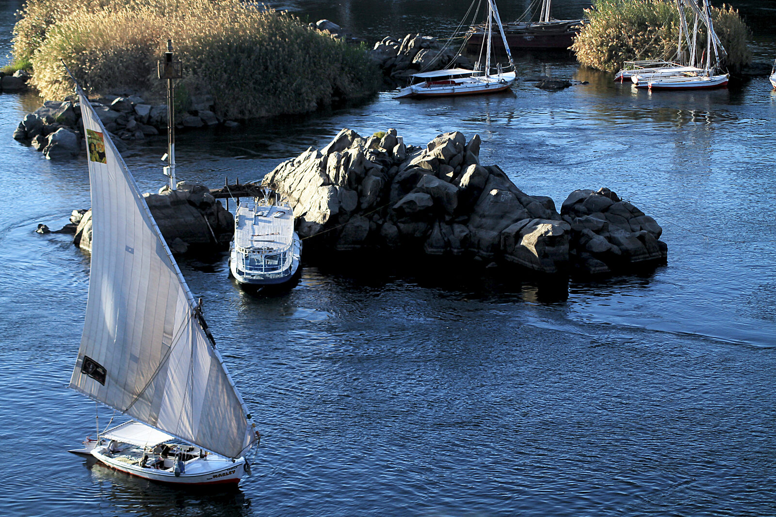 Traditional feluccas sailing on the Nile around the granite rocks at Aswan in Upper Egypt