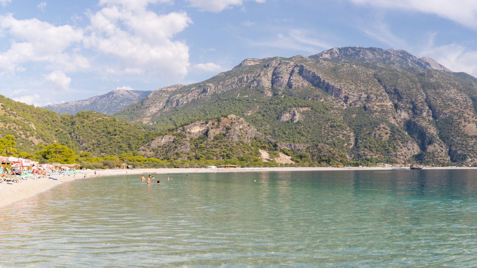 The turquoise lagoon and sandy beach at Oludeniz on Turkey's Mediterranean coast, backed by pine-covered mountains