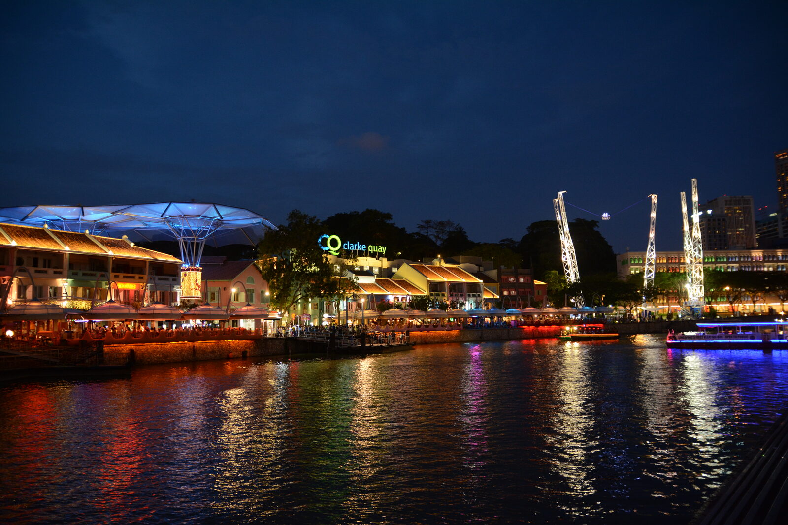 Clarke Quay riverside restaurants and bumboats lit up at night in Singapore