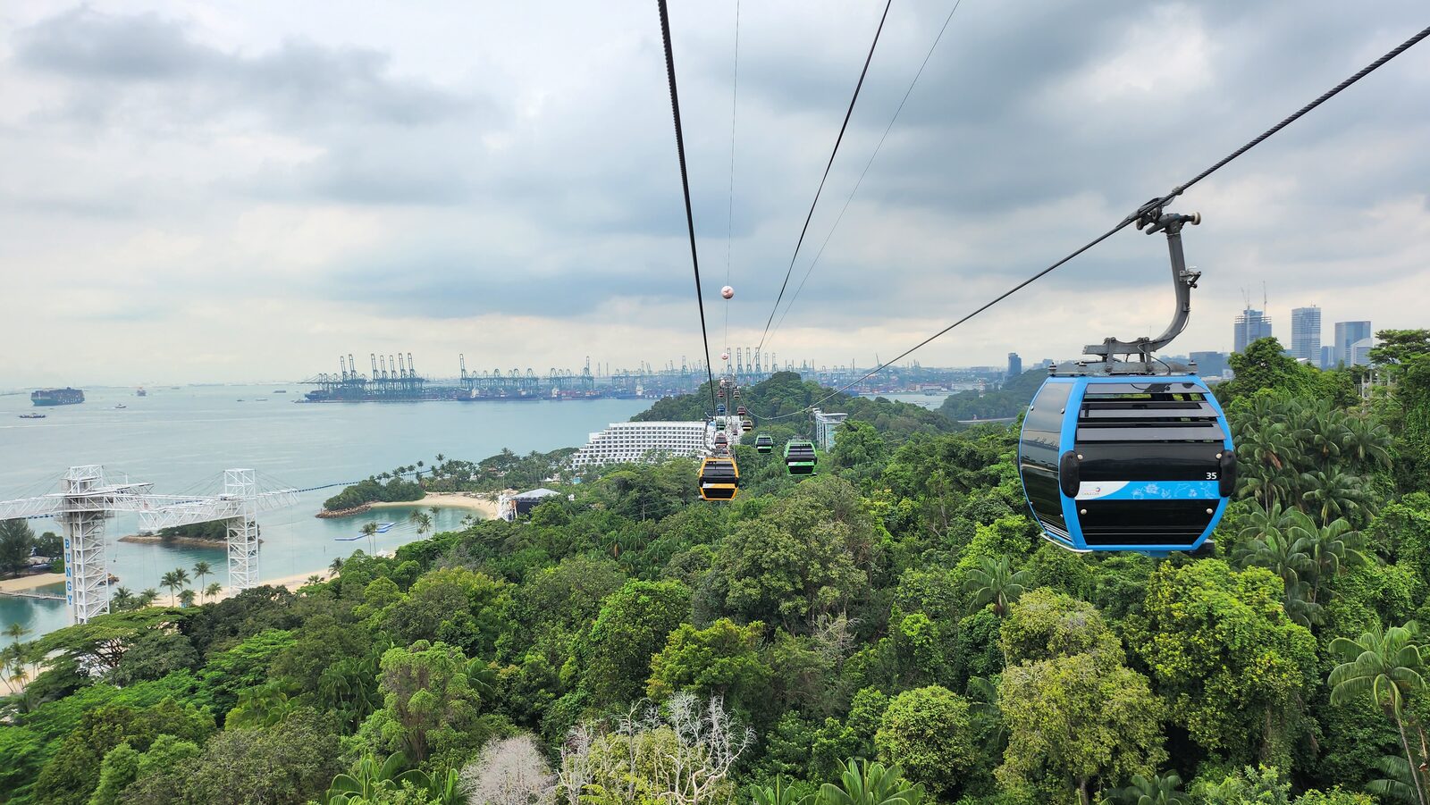 Sentosa cable car gliding over green hills and the harbour in Singapore