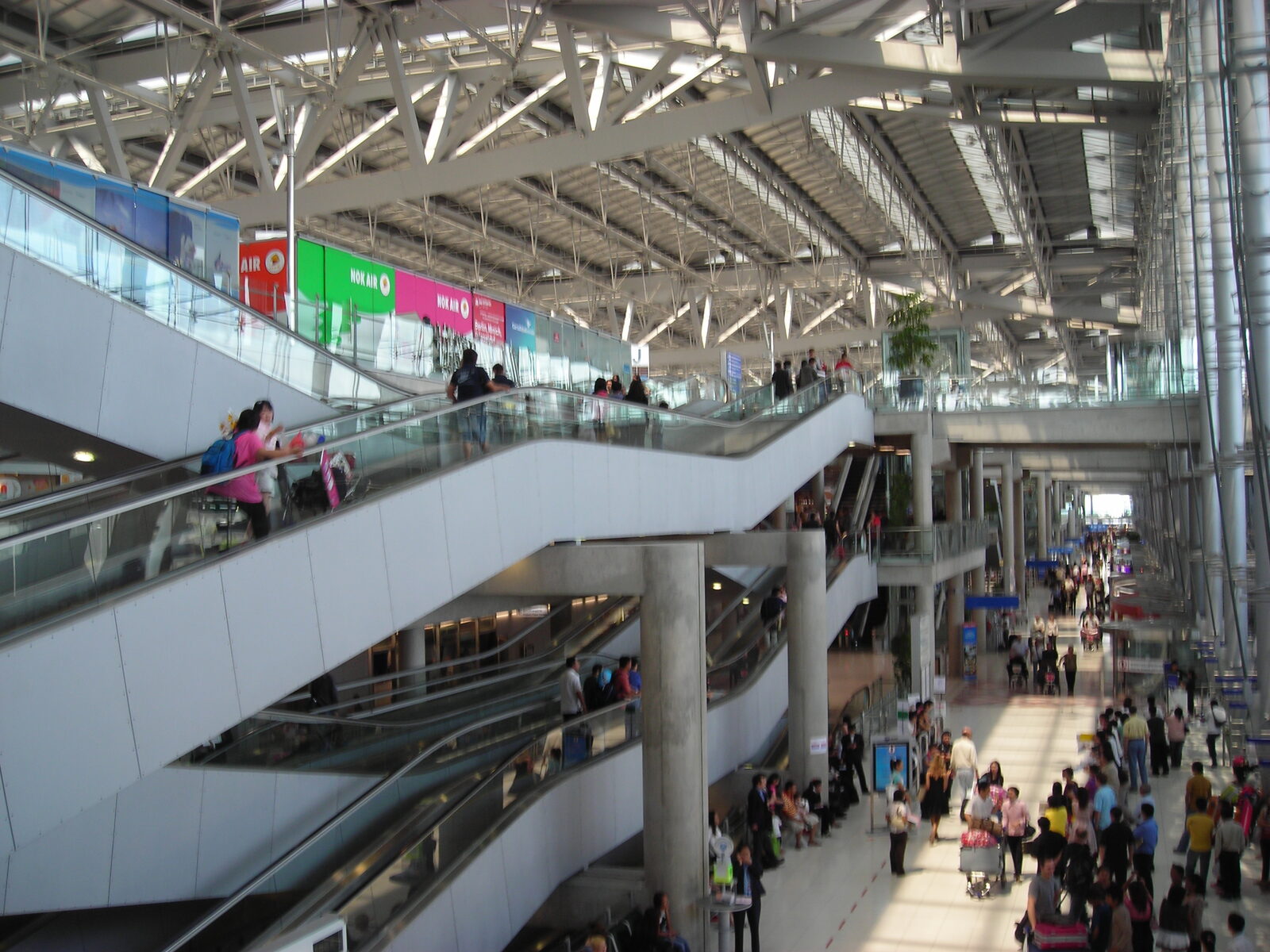 Interior of Suvarnabhumi Airport (BKK) main terminal with escalators and travellers