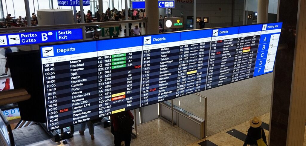 A large airport departure board listing international flights across many destinations