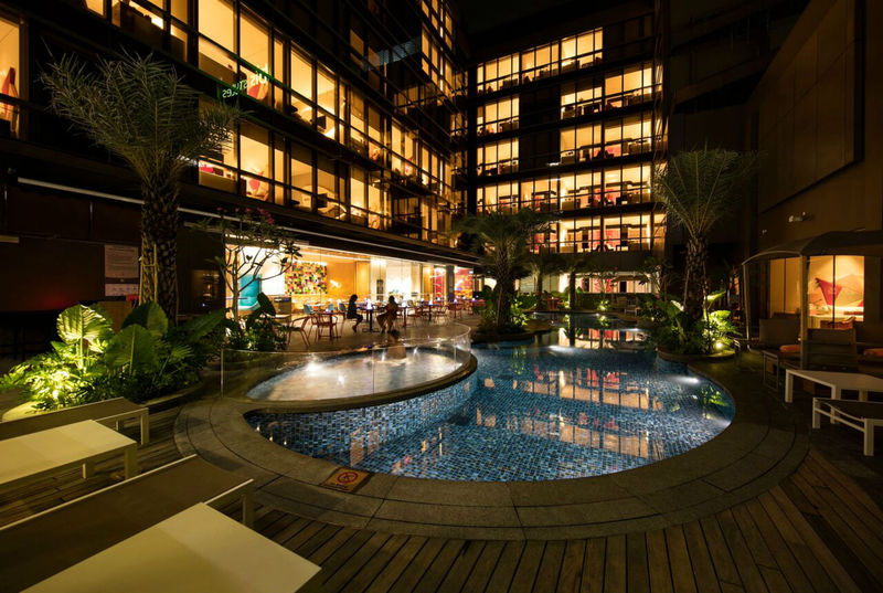 Swimming pool lit at night beneath the ibis Styles Singapore On Macpherson