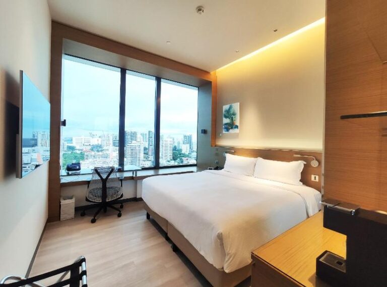 Guest bedroom with floor-to-ceiling city view at One Farrer Hotel Singapore