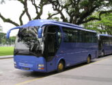 A blue tour coach parked under trees in Singapore, ready for a group transfer